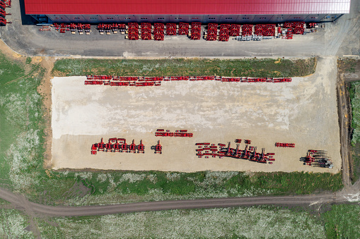 The territory of an industrial plant. Large hangars with a red roof. Aerial view, daytime shooting.