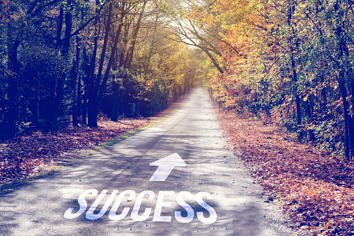 A road and a directional arrow pointing towards success