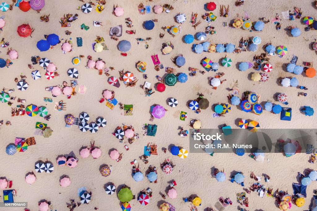 Top View of Colourful Umbrellas and People Relaxing at the Beach on a Sunny Day, Copacabana, Rio de Janeiro, Brazil Rio de Janeiro, Brazil, aerial top view of Copacabana Beach showing colourful umbrellas and people relaxing on a summer day. Tropical travel and vacation concept. Beach Stock Photo