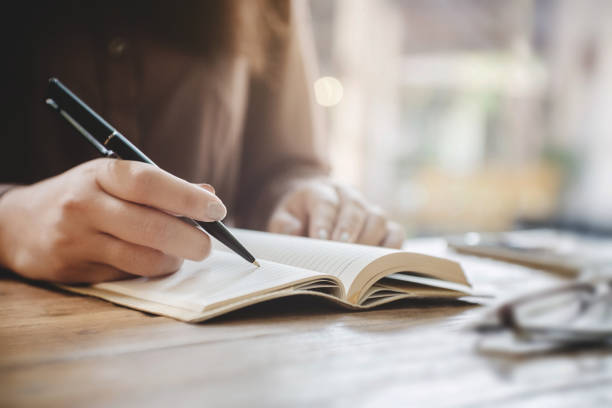 istock close up female hands writing on notebook at cafe 1097918434