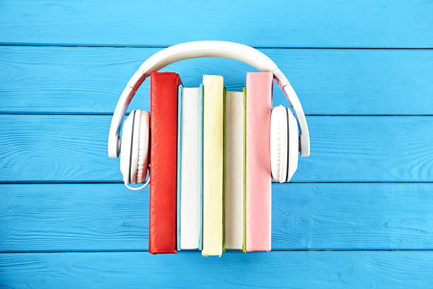 áudio vs. conceito de livro de papel. leitura contra a ouvir. livros e fones de ouvido na tabela. - hardcover book audio - fotografias e filmes do acervo