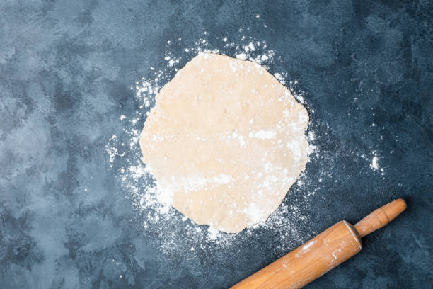 istock Female hands rolling dough on a table with a wooden rolling pin. Top view. Flat lay. 1097922704