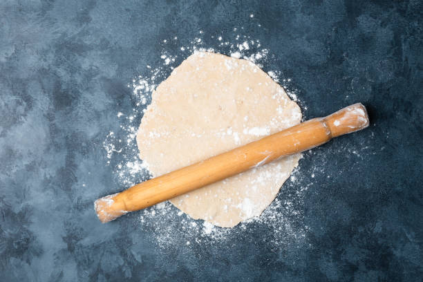 istock Female hands rolling dough on a table with a wooden rolling pin. Top view. Flat lay. 1097929432