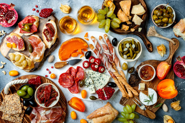 istock Appetizers table with antipasti snacks and wine in glasses. Brushetta or authentic traditional spanish tapas set, cheese and meat platter over grey concrete background. Top view 1097932466
