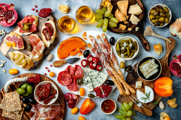 istock Appetizers table with antipasti snacks and wine in glasses. Brushetta or authentic traditional spanish tapas set, cheese and meat platter over grey concrete background. Top view 1097932506