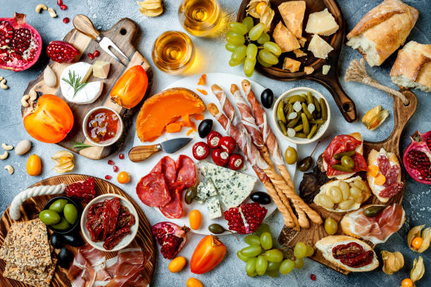 istock Appetizers table with antipasti snacks and wine in glasses. Brushetta or authentic traditional spanish tapas set, cheese and meat platter over grey concrete background. Top view 1097932510