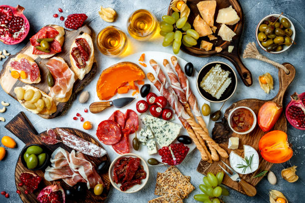 istock Appetizers table with antipasti snacks and wine in glasses. Brushetta or authentic traditional spanish tapas set, cheese and meat platter over grey concrete background. Top view 1097933570
