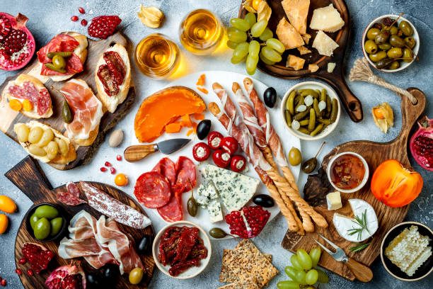 istock Appetizers table with antipasti snacks and wine in glasses. Brushetta or authentic traditional spanish tapas set, cheese and meat platter over grey concrete background. Top view 1097933586