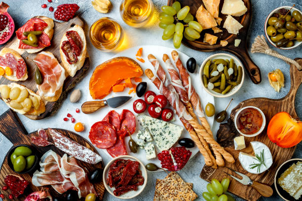 istock Appetizers table with antipasti snacks and wine in glasses. Brushetta or authentic traditional spanish tapas set, cheese and meat platter over grey concrete background. Top view 1097933612