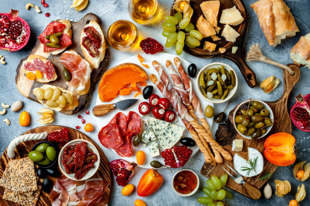 istock Appetizers table with antipasti snacks and wine in glasses. Brushetta or authentic traditional spanish tapas set, cheese and meat platter over grey concrete background. Top view 1097934674