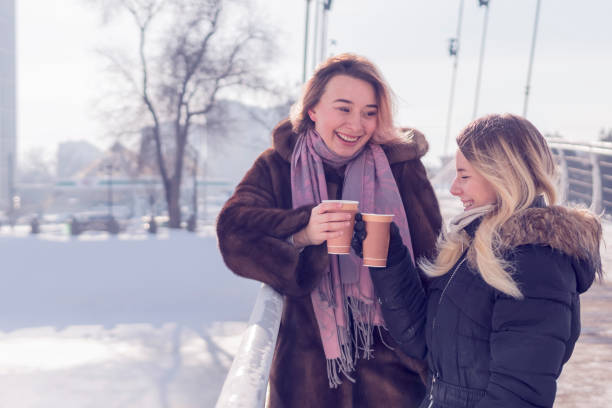 istock two laughing women with cups of coffee 1097940348