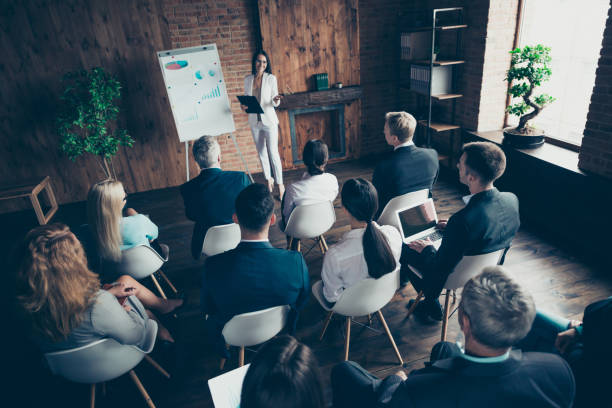 istock Above high angle view of classy clever smart speaker presenter trainee speaking to business people listening sitting on chairs finance economy company at loft interior workplace station open space 1097946404