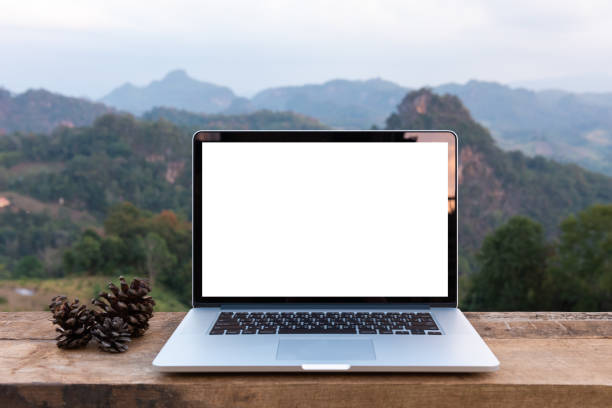 istock Laptop computer and pine cones on wooden table with mountain view 1097947474