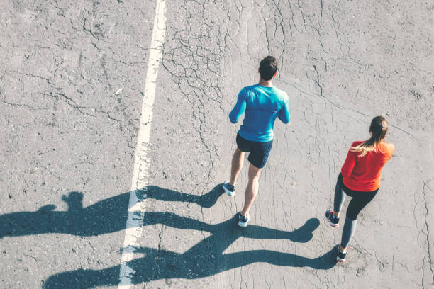 istock aerial view on couple running on asphalt 1097948608