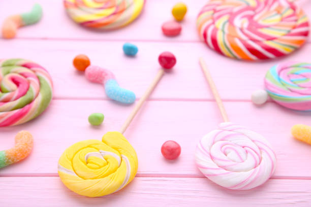 istock Colorful lollipops and different colored round candy on pink wooden background 1097948648