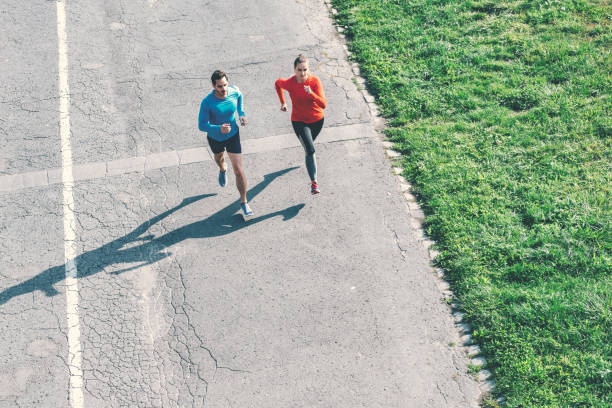 istock aerial view on couple running on asphalt 1097948678