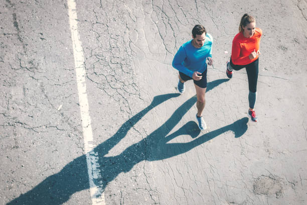 istock aerial view on couple running on asphalt 1097948756