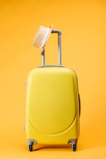 istock travel bag with wheels and straw hat on yellow background 1097952352