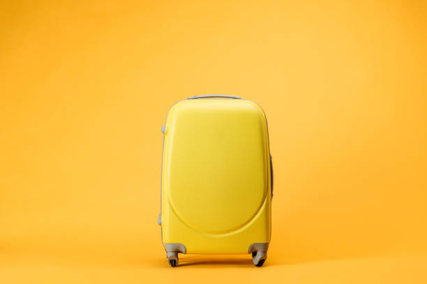 borsa da viaggio con ruote su sfondo giallo - valigia a rotelle foto e immagini stock