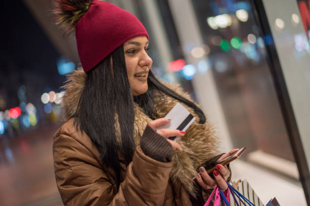 istock Young woman using mobile phone and credit card while shopping 1097954648