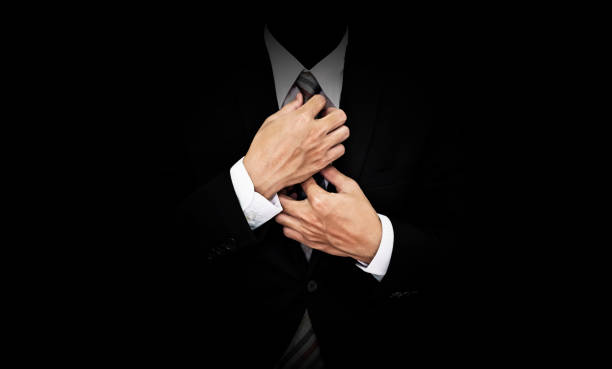 homme d’affaires en costume noir, cravate, sur fond noir de toucher - smoking issues photos photos et images de collection