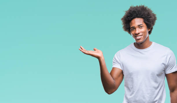 istock Afro american man over isolated background smiling cheerful presenting and pointing with palm of hand looking at the camera. 1097963248