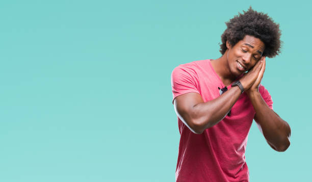 istock Afro american man over isolated background sleeping tired dreaming and posing with hands together while smiling with closed eyes. 1097967160