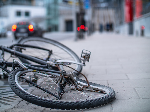 An old broken and bent bicycle with a rusted chain discarded in the street