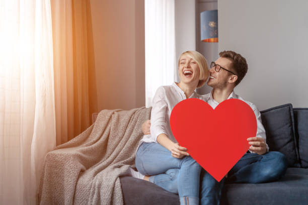istock Laughing couple with heart on sofa 1097970684