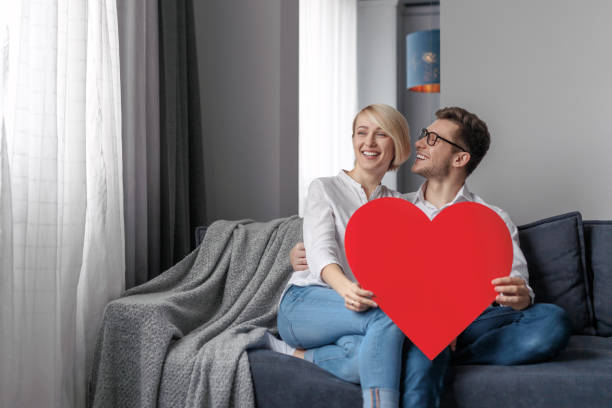 istock Smiling couple with heart relaxing on couch 1097970686