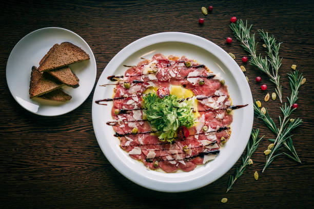 Salad of veal carpaccio and toast close-up on a wooden table