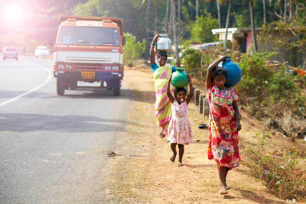 rural Indian women carry water on their heads in traditional pots India, Hampi - March 18, 2017: rural Indian women carry water on their heads in traditional pots, EDITORIAL. village maharashtra stock pictures, royalty-free photos & images