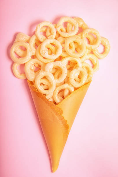 Close up of Cheese Potato Puff Snacks sticks, Popular Ready to eat crunchy and puffed snacks sticks  cheesy salty pale-yellow color over white background
