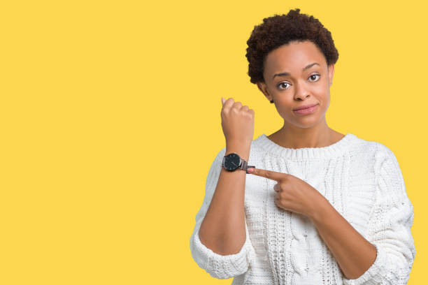 急いで、時計時間、焦り、動揺するポインティング、および期限遅れの怒っている孤立した背景の上にセーターを着ている美しい若いアフリカ系アメリカ人女性 - checking the time women impatient wristwatch ストックフォトと画像