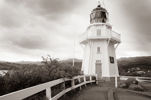 AKAROA NEW ZEALAND - OCTOBER 13 2018; Vintage sepia toned image lighthouse at Akaroa Head on cloudy day Banks Peninsula South Island New Zealand