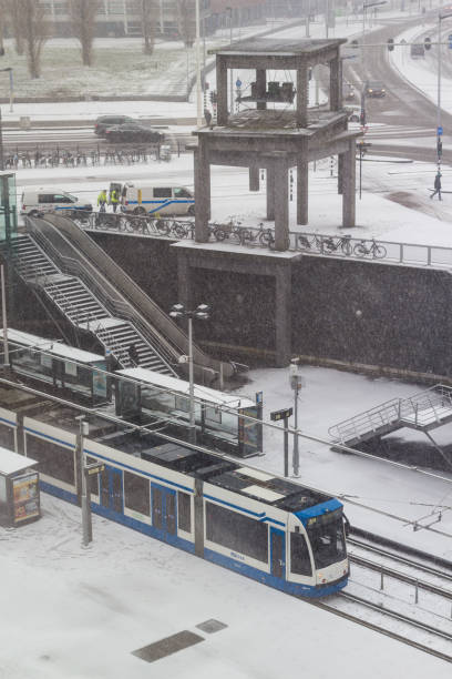 tram in Amsterdam during snowfall Amsterdam, the Netherlands - January 22 2019: GVB fast tram riding through Amsterdam in snow view from above tasrail stock pictures, royalty-free photos & images