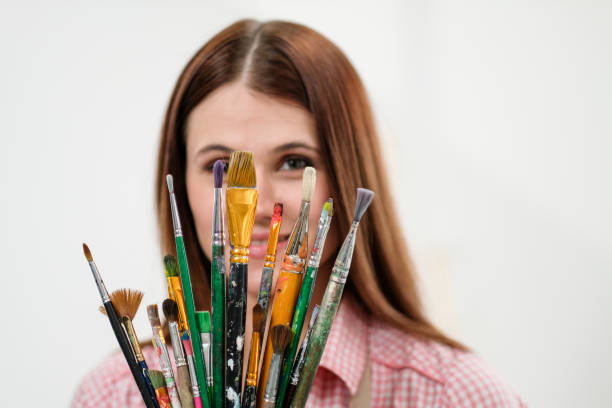 istock Young woman artist with brushes and paints in a white studio. 1098009254