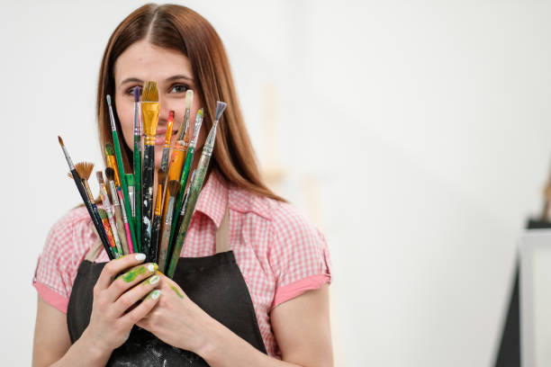 istock Young woman artist with brushes and paints in a white studio. 1098009368