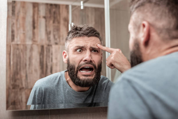 giovane che si sente emotività nel vedere l'acne sul suo viso - overemotional foto e immagini stock