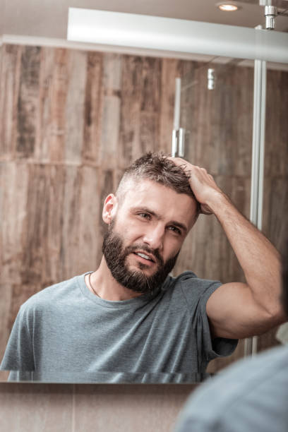 istock Young businessman wearing grey shirt looking into mirror 1098010016