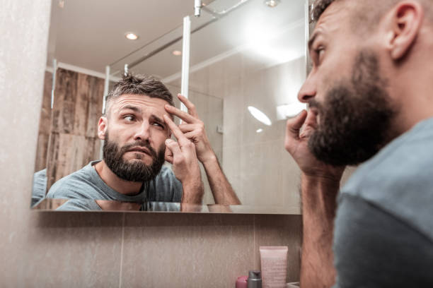 istock Bearded dark-haired man looking at acne on his face 1098010038