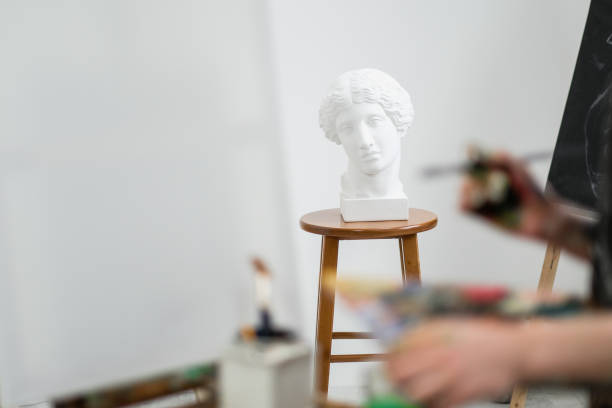 istock Young beautiful girl painter in a white studio draws on an easel on canvas. 1098011922