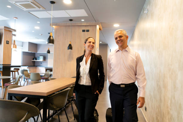 istock Cheerful business couple leaving hotel each pulling their suitcases laughing and talking 1098012680