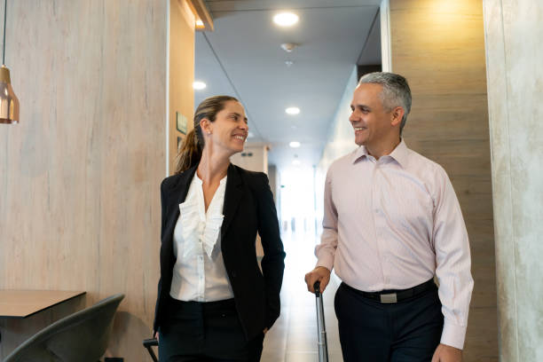 istock Happy business couple looking at each other while leaving hotel smiling 1098012690