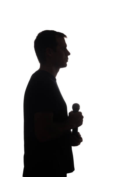 istock Young man with microphone in his hands - silhouette 1098016064