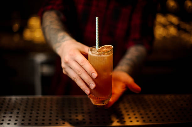 istock Bartender serving a Singapore Sling cocktail with orange zest 1098018678