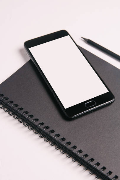 istock Black smartphone and notebooks on light background. Top view 1098021548