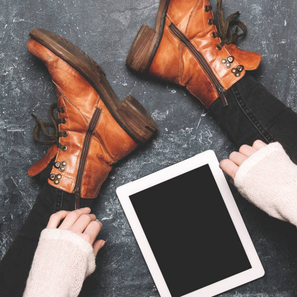 istock Female legs shod in Hiking boots and tablet pc. Mockup for text or apps 1098021606