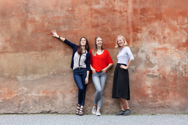 istock Three confident young women standing on a red wall 1098021816