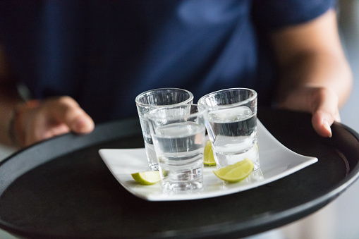 Close-up of unrecognizable waiter serving tequila shots
